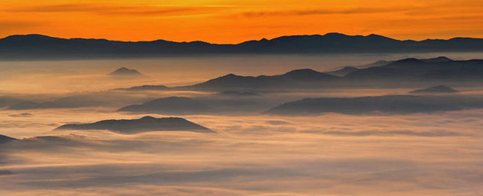 Scenic view of mountains against dramatic sky during sunset