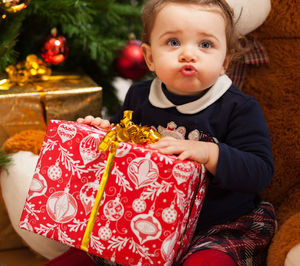 Cute girl with stuffed toy and gifts against christmas tree at home