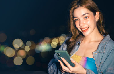 Young woman using mobile phone at night