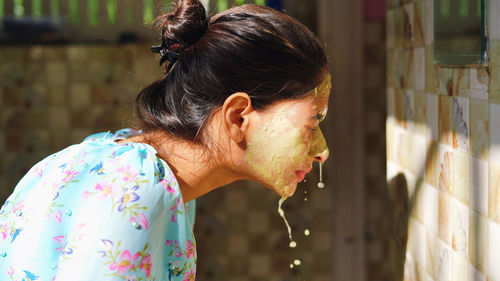 Beautiful woman is washing facial mask in bathroom after applying face mask.