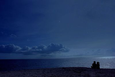 Rear view of man on beach against sky at night