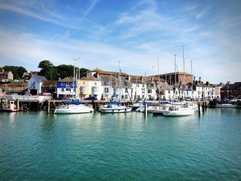 Boats moored at harbor against sky