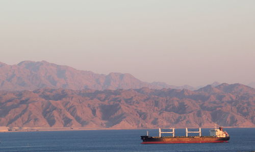 Scenic view of sea and mountains against clear sky