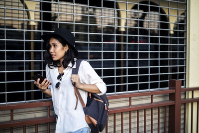 Full length of woman standing against brick wall