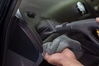 Cropped hand cleaning air conditioner in car