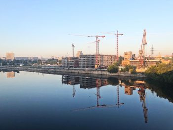 Reflection of cranes in river against sky
