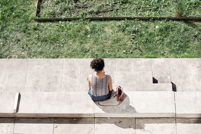 Rear view of woman sitting on brick wall