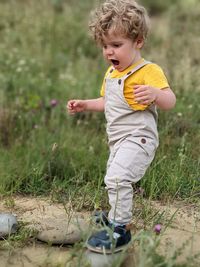 Full length of boy playing with arms outstretched on field