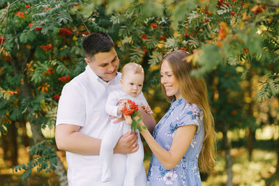 A european family in the park on a summer day. mom, dad and little son are smiling in their arms 