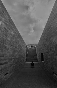 Rear view of man walking on alley amidst buildings in city