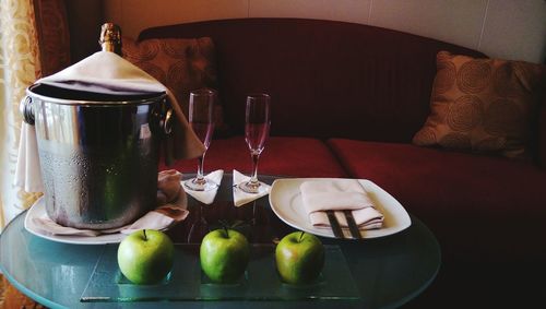 Champagne bottle in ice bucket by granny smith apples on table in cruise ship