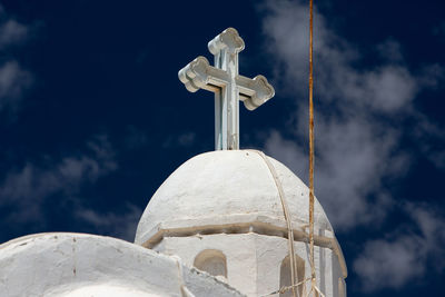 Low angle view of church dome with cross against cloudy sky