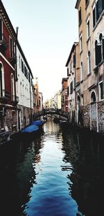 Canal amidst buildings against sky in city