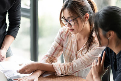 Young woman using phone while sitting on table