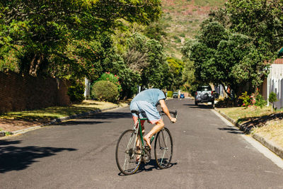 Rear view of man riding bicycle on road