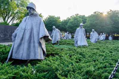 Statues on field against sky