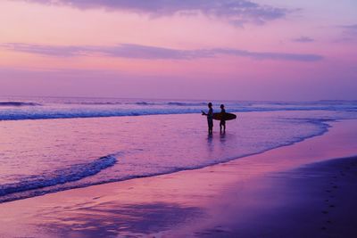 Silhouette person on beach against sky during sunset