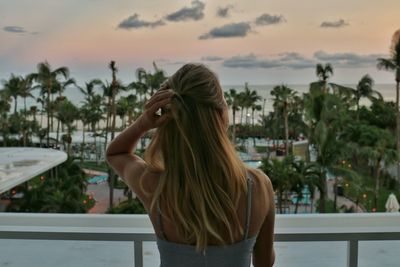 Rear view of woman against trees during sunset