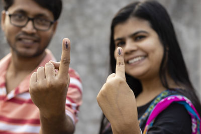 Indian man and woman showing ink-marked fingers with smiling faces after casting vote