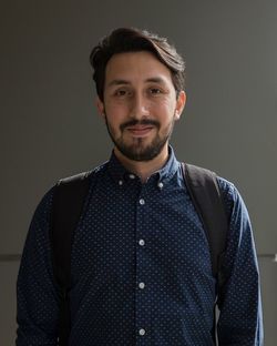 Portrait of man with backpack standing against wall