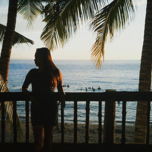 Young woman leaning on railing at beach