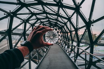 Low angle view of man holding crystal on metallic bridge