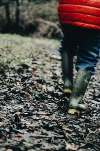 Low section of woman walking on autumn leaves