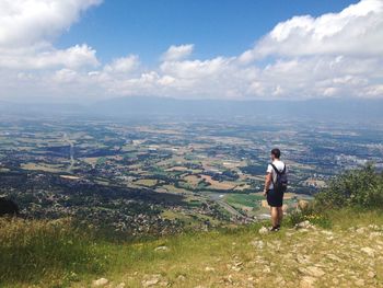 Full length of man standing on mountain against cloudy sky