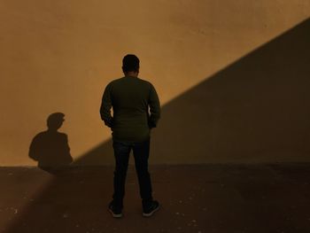 Rear view of silhouette man standing against orange sky