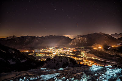 Aerial view of illuminated snowcapped mountains against sky at night