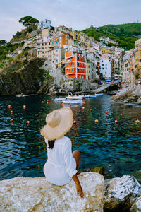 Rear view of woman sitting by water in city