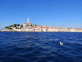 View of building in sea against clear blue sky