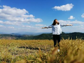 Woman standing on field against sky