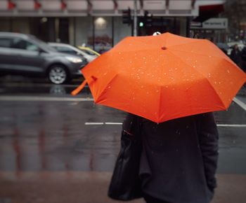 Close-up of wet red umbrella in city during rainy season