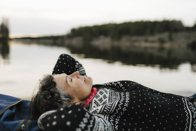 Caucasian female hiker resting by lake during vacation