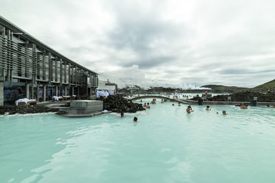 People swimming in pool against sky