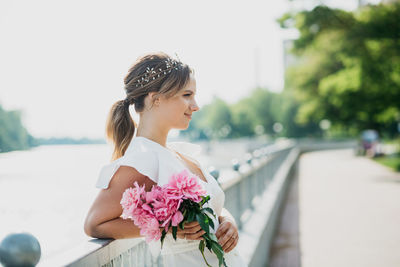 Side view of woman standing by pink flowering plants