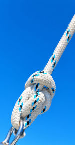 Low angle view of rope tied up against blue sky