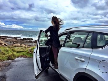 Women looking at beach standing on car`