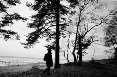 Rear view of man standing by sea against sky