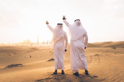 Rear view of people standing on desert against sky