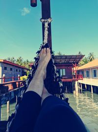 Low section of woman in canal against clear sky