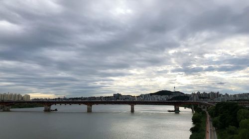 Bridge over river in city against sky