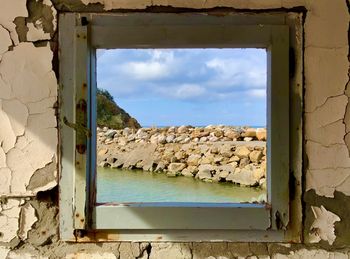 Old building against sky seen through window