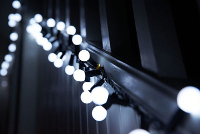 Low angle view of illuminated light bulbs hanging from staircase