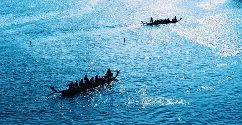 Silhouette people on boat in sea