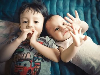 High angle view of cute siblings lying on bed