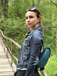 Portrait of woman with backpack standing on footbridge