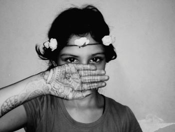 Portrait of girl wearing tiara showing henna tattoo against wall at home