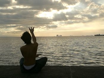 Woman sitting on beach by sea against sky